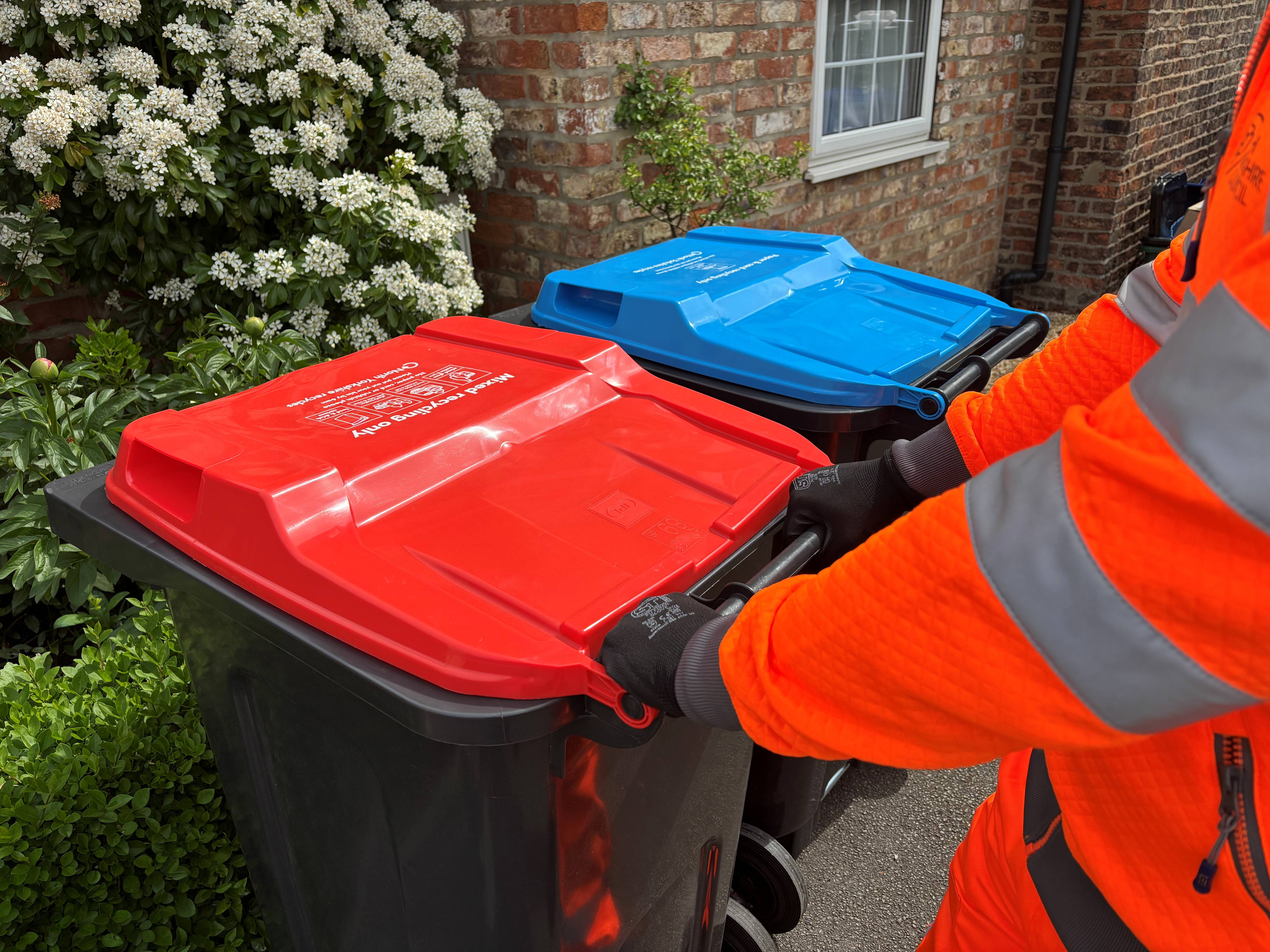 Photo showing two wheelie bins. One with a red lid and one with a blue lid Photo showing two wheelie bins. One with a red lid and one with a blue lid